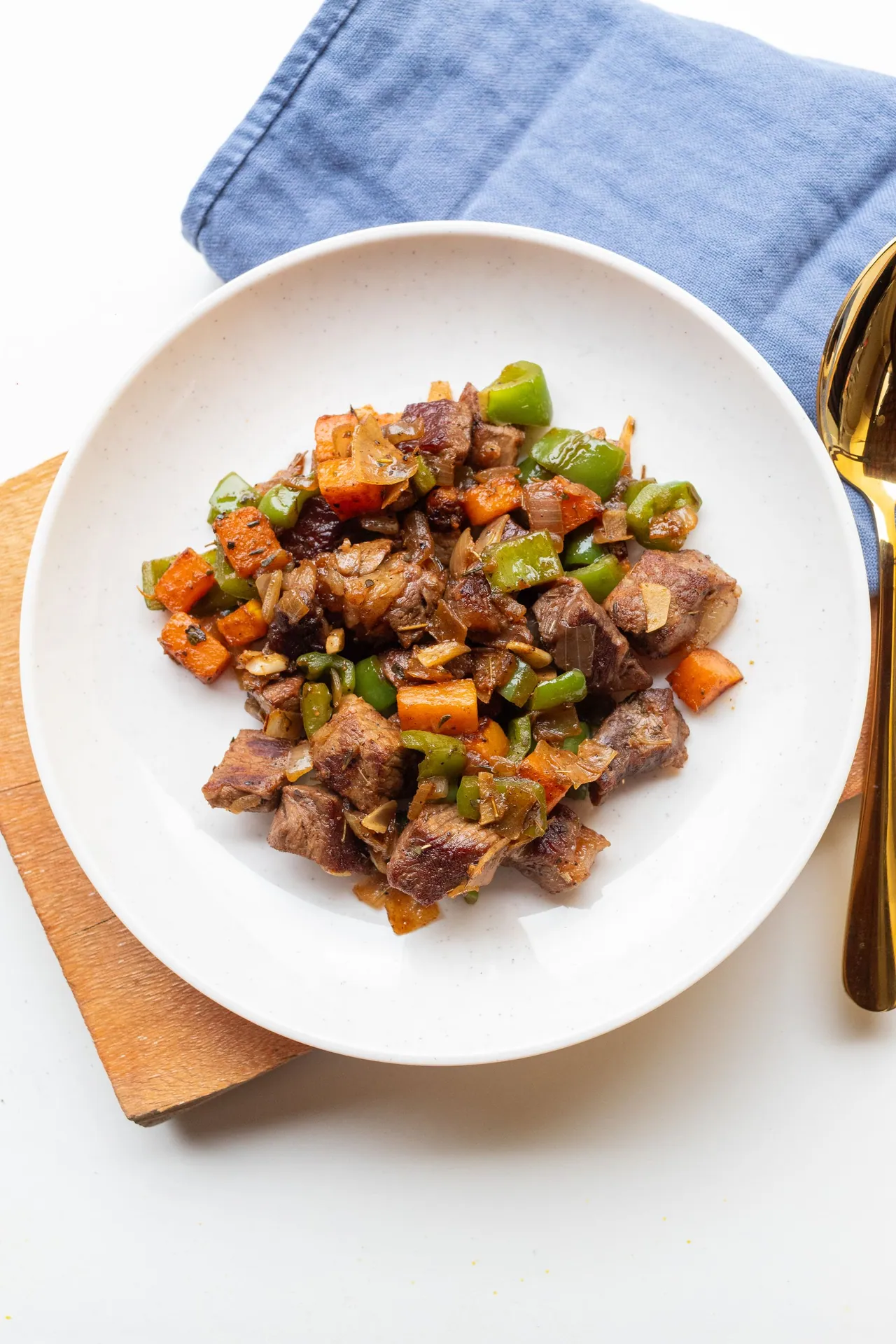 Seared beef strips with grilled vegetables on a white plate