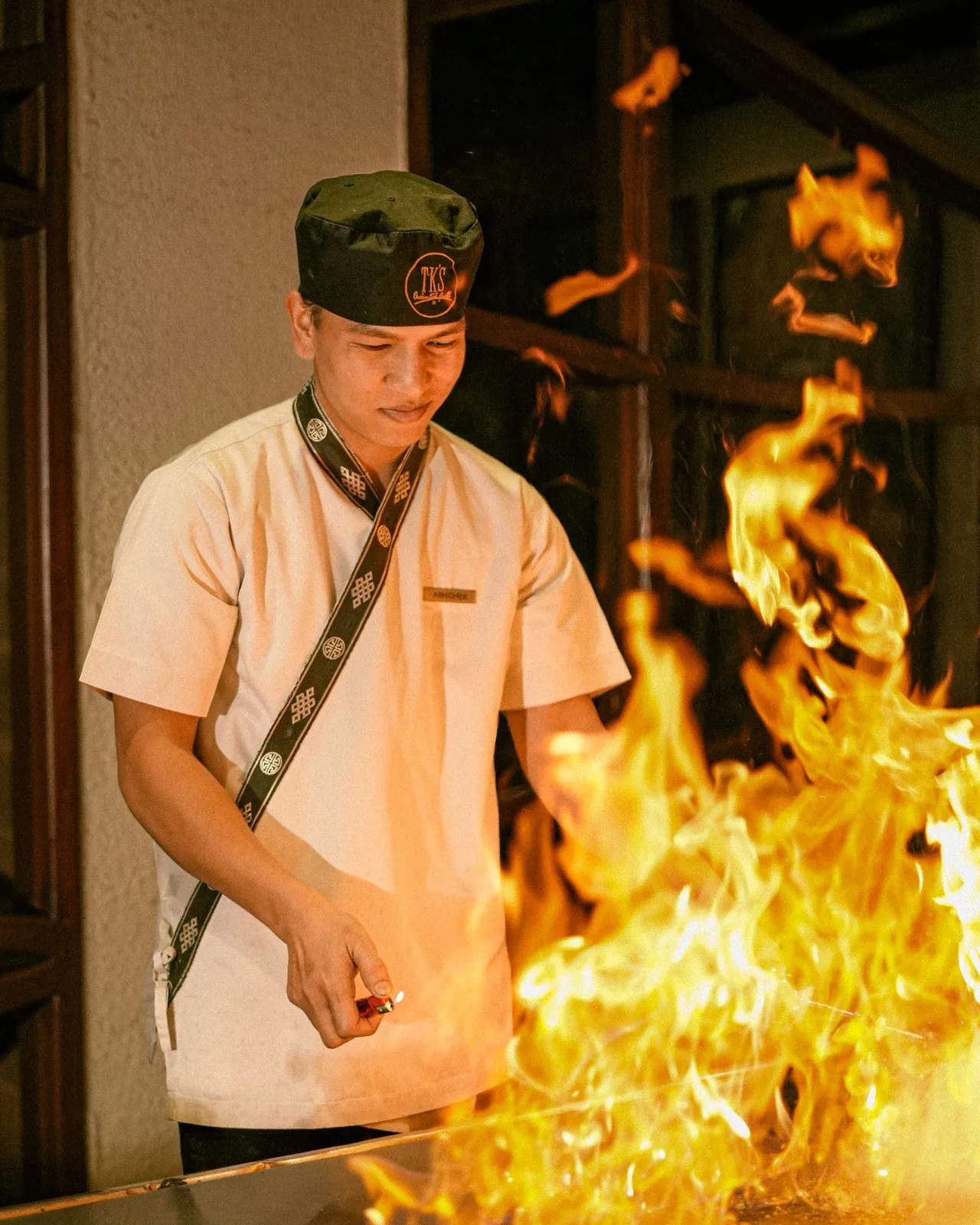 A hibachi chef cooking with flames on a teppanyaki grill